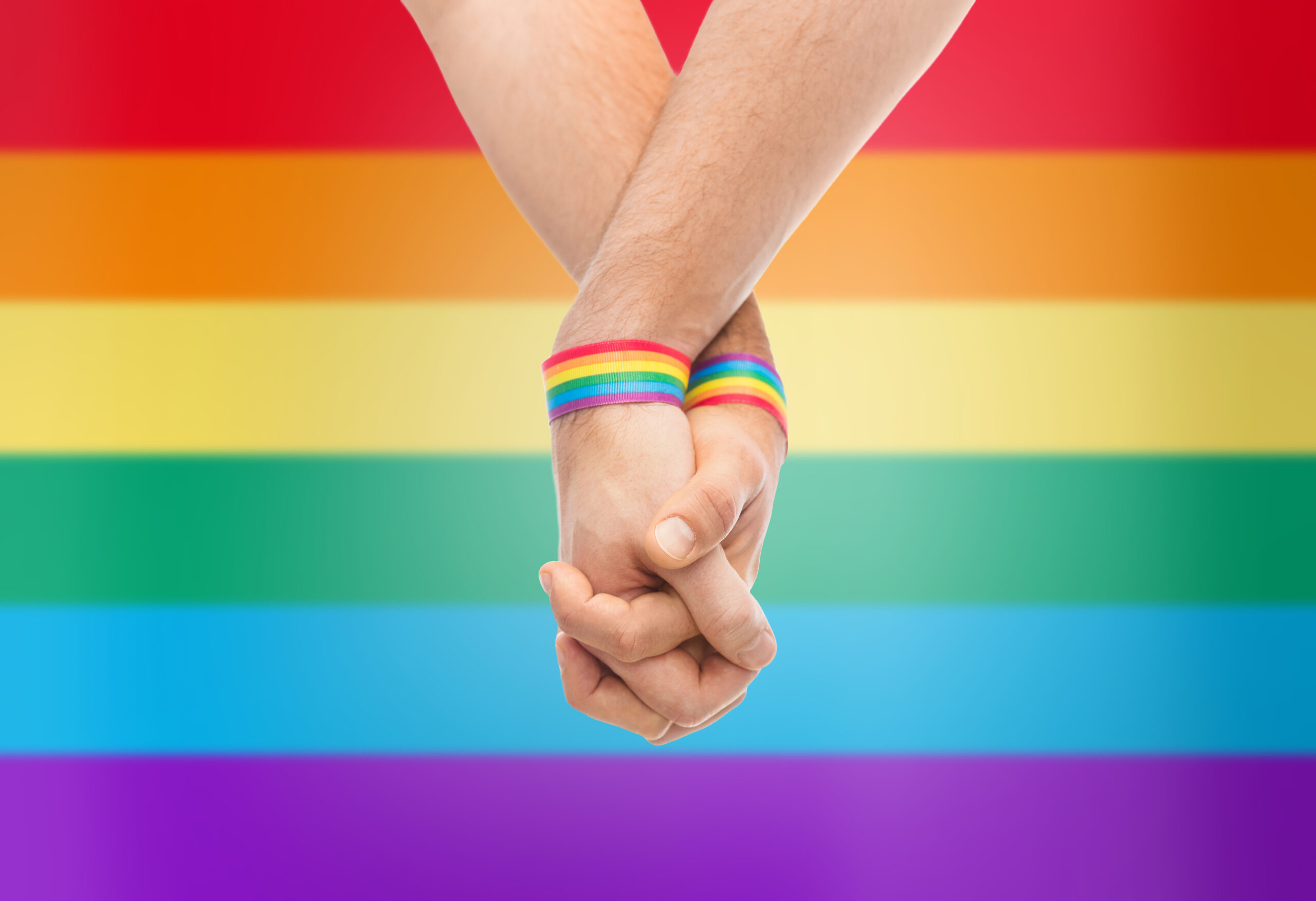 hands of couple with gay pride rainbow wristbands